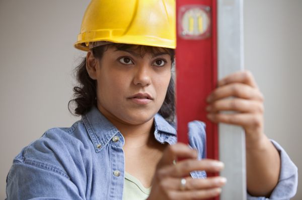 زن کارگر ساختمانی در اندازه گیری سطح خواندن کلاه
