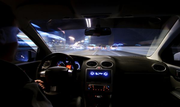 جاده شبانه نمایی از داخل ماشین نور طبیعی خیابان و ماشین های دیگر حرکت تار است