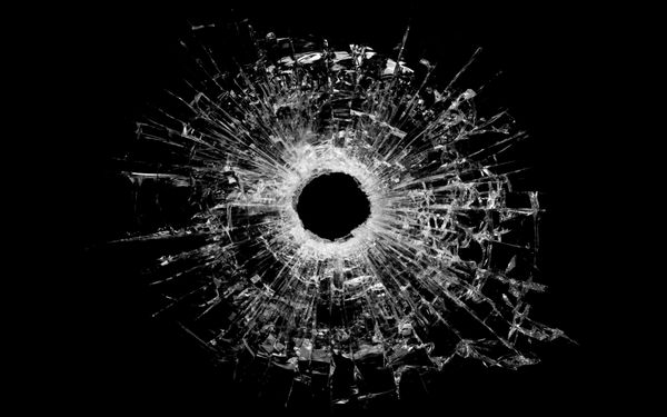سوراخ گلوله در شیشه - نمای نزدیک سوراخ گلوله واقعی و جدا شده روی سیاه