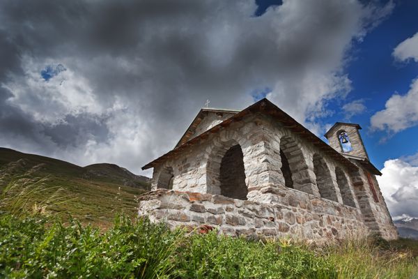 یک کلیسای کوچک در کوه بلند در طول تابستان با آسمان ابری