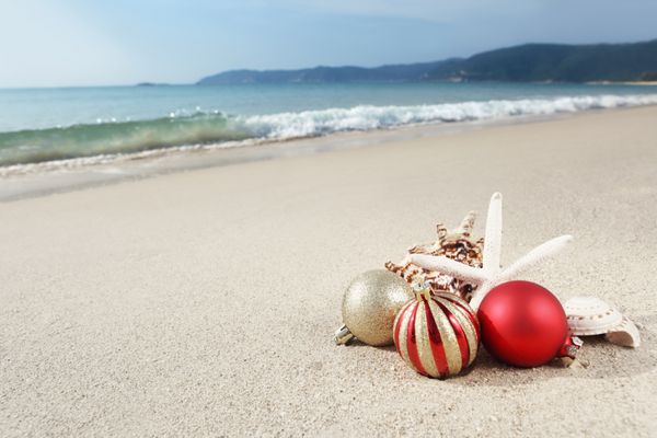 توپ های کریسمس و صدف های دریایی در ساحل نزدیک دریا