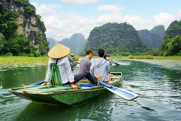 گردشگران در قایق قایقران با استفاده از پاهای خود برای به حرکت درآوردن پاروها ویتنام