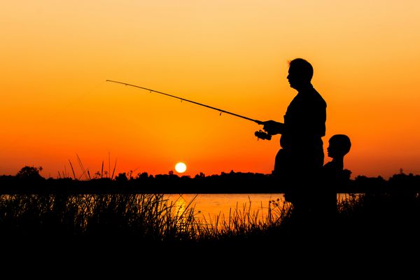 ماهیگیری پدر و پسر در پس زمینه غروب رودخانه