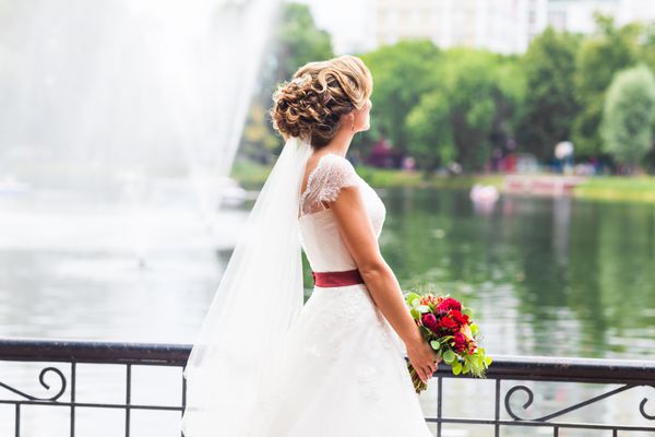 گل عروسی زنی که دسته گل رنگارنگ را در روز عروسی با دستانش نگه داشته است