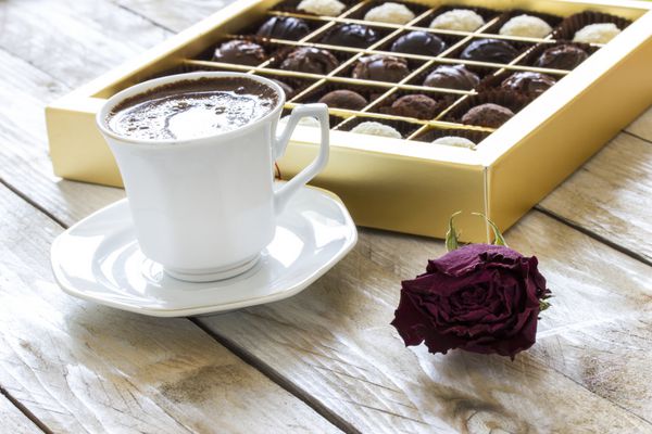 قهوه ترک شکلات ترافل و گل رز خشک روی میز چوبی