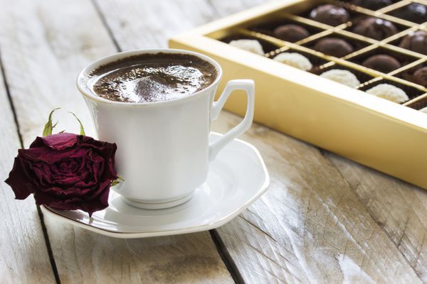 قهوه ترک شکلات ترافل و گل رز خشک روی میز چوبی