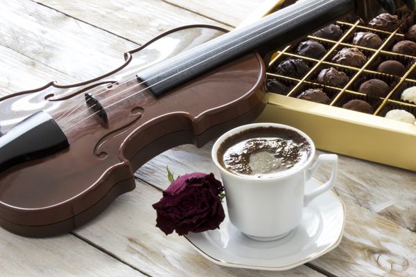 قهوه ترک شکلات ترافل ویولن و رز قرمز خشک شده روی میز چوبی