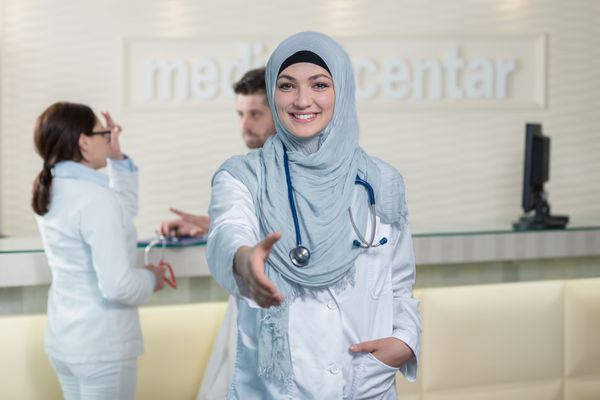 خانم دکتر مسلمان جوان خندان و خوشحال که برای دست دادن دست می دهد