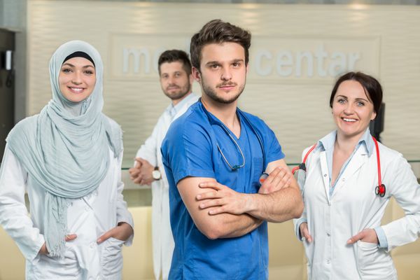 مفهوم مراقبت های بهداشتی و پزشکی - پزشک مرد جذاب در مقابل گروه پزشکی در بیمارستان که شست را نشان می دهد