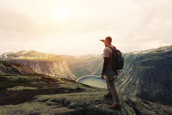مسافر جوان شجاع در بالای یک فلات کوه به دوردست نگاه می کند