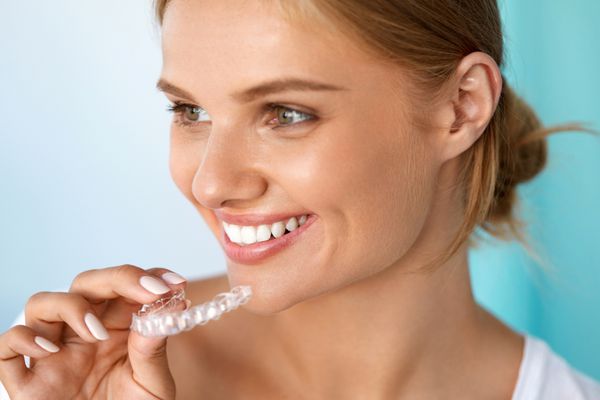 زن خندان با لبخند زیبا با استفاده از سینی سفید کننده دندان تصویر با وضوح بالا