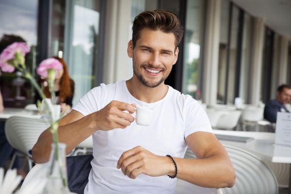 پرتره مرد جوان خوش تیپ در حال نوشیدن قهوه