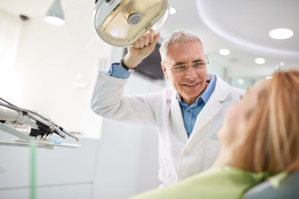 دندانپزشک قبل از شروع کار نور سرکش را تنظیم می کند