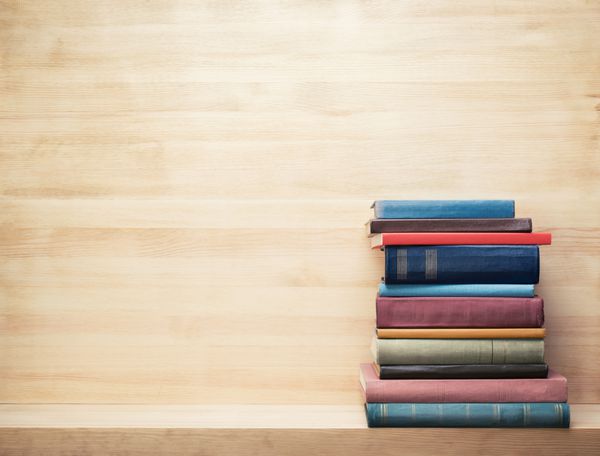 کتاب های قدیمی روی یک قفسه چوبی