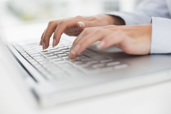 نمای نزدیک از دست ها در حال تایپ روی صفحه کلید لپ تاپ در دفتر