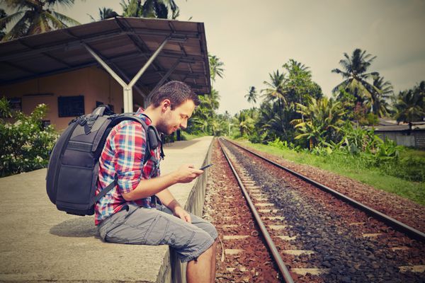 مسافر جوان با تلفن همراه در راه آهن