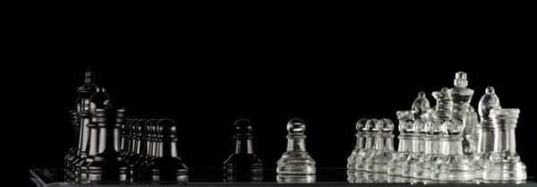 مهره های شطرنج شیشه ای روی صفحه شطرنج شیشه ای روی پس زمینه سیاه