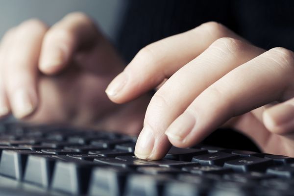 دست های زن در حال تایپ کردن روی صفحه کلید کامپیوتر