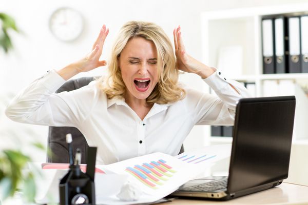 زن تاجر استرسی که با صدای بلند روی لپ تاپ در دفتر فریاد می زند