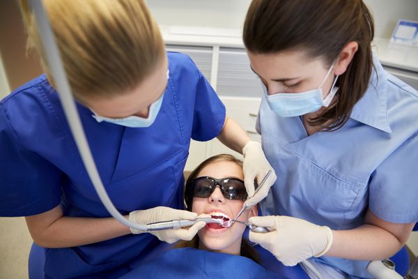مردم پزشکی دهان و دندان و مفهوم مراقبت های بهداشتی - دندانپزشکان زن با آینه مته و پروب در حال درمان دندان های دختر بیمار در مطب کلینیک دندانپزشکی