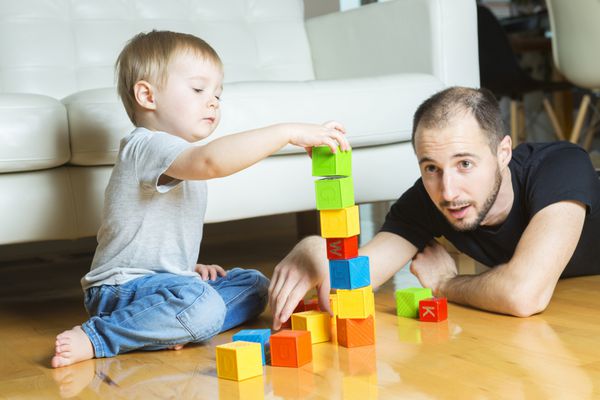 یک پدر با پسرش در خانه بلوک بازی می کند