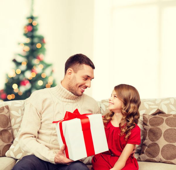 خانواده کریسمس کریسمس زمستان شادی و مفهوم مردم - پدر و دختر خندان جعبه هدیه را در دست گرفته و به یکدیگر نگاه می کنند