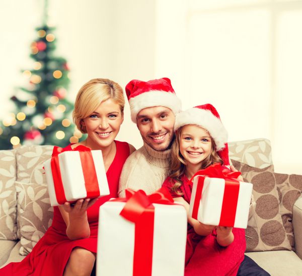 خانواده کریسمس کریسمس زمستان شادی و مفهوم مردم - خانواده خندان در کلاه کمکی بابا نوئل با جعبه های هدیه بسیاری
