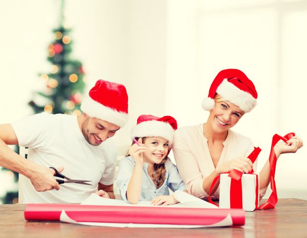 مفهوم کریسمس کریسمس زمستان خانواده شادی و مردم - خانواده خندان در کلاه کمکی بابا نوئل با جعبه هدیه