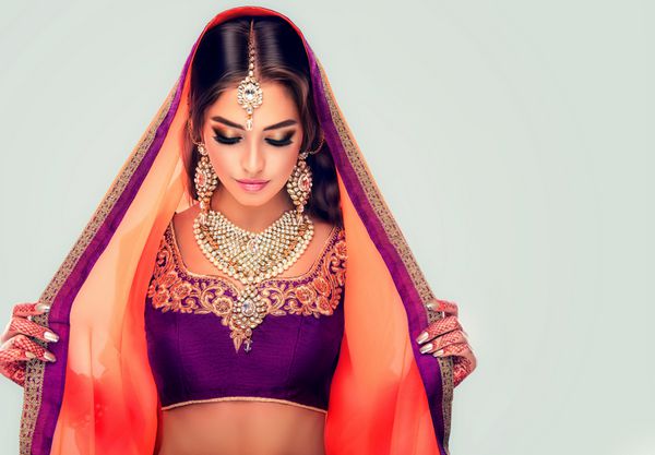 پرتره دختر زیبای هندی مدل زن جوان هندو با جواهرات مهندی و کوندان تاتو لباس سنتی هندی lehenga choli