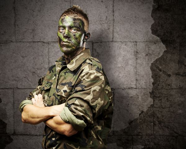 پرتره سرباز جوان با رنگ استتار جنگل در پس زمینه آجر گرانج