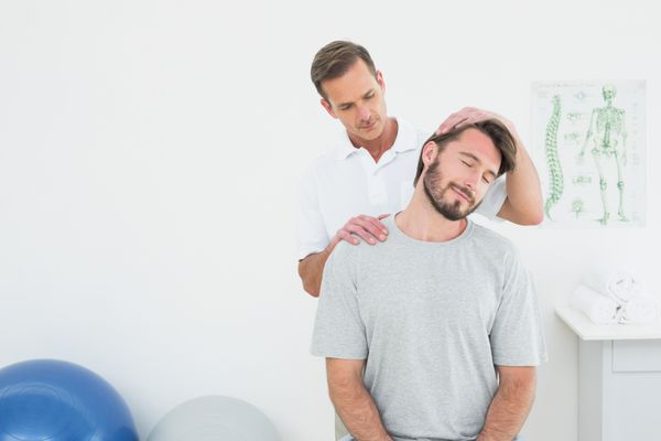 متخصص کایروپراکتیک مرد در حال انجام تنظیم گردن در مطب