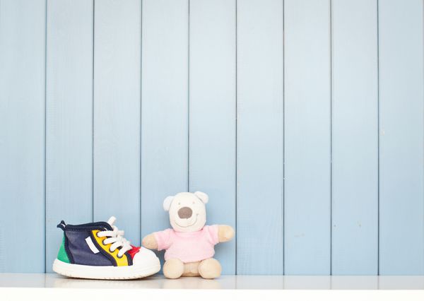 کفش های کوچک بچه و خرس عروسکی روی میز اتاق کودک