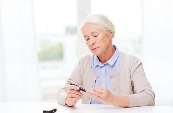 پزشکی سن دیابت مراقبت های بهداشتی و مفهوم مردم - زن مسن با گلوکومتر که سطح قند خون را در خانه چک می کند