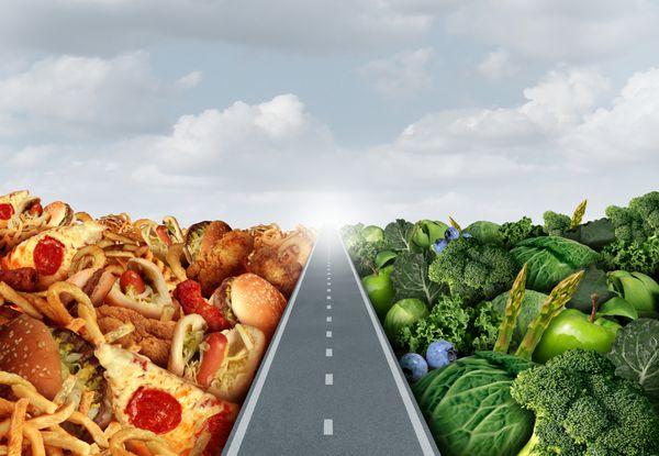 مفهوم سبک زندگی رژیم غذایی یا نماد تصمیم گیری تغذیه و انتخاب غذا دوراهی بین میوه و سبزیجات تازه سالم سالم یا فست فود غنی از کلسترول چرب با جاده یا مسیری بین