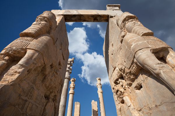 مجسمه های غول پیکر لاماسوی نگهبان دروازه همه ملل در برابر آسمان آبی با ابرهای سفید درخشان دراماتیک در تخت جمشید باستان پایتخت امپراتوری هخامنشی در شیراز ایران