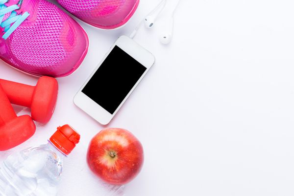 مفهوم تناسب اندام با تلفن همراه حوله کفش دمبل سیب قرمز و کفش ورزشی زنانه روی پس زمینه سفید نمای از بالا