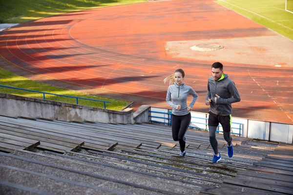 تناسب اندام ورزش ورزش و مفهوم سبک زندگی - زوج شادی که در طبقه بالا در استادیوم می دوند