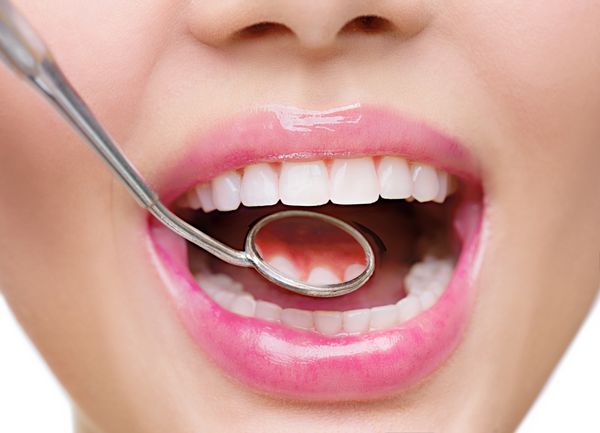 دندان های زن سفید سالم و آینه دهان دندانپزشک از نزدیک جدا شده بر روی پس زمینه سفید بهداشت دندان مفهوم مراقبت از دهان