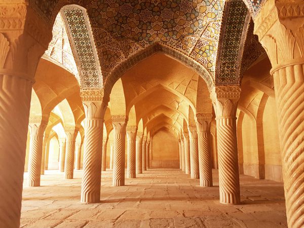 مصلای مسجد وکیل با ستون های مارپیچ از سنگ و کاشی کاری سقف منور با نور خورشید واقع در شیراز ایران