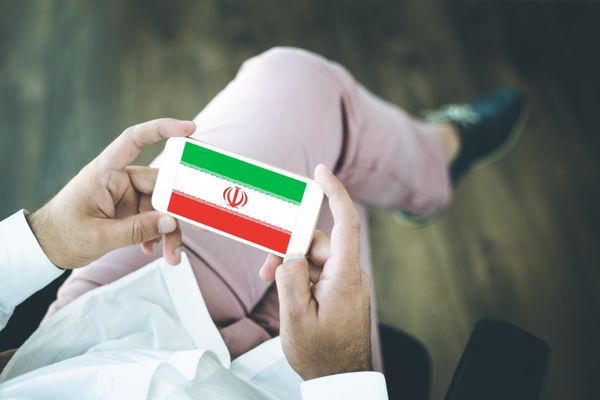افرادی که از تلفن هوشمند استفاده می کنند و پرچم ایران را روی صفحه نمایش می دهند