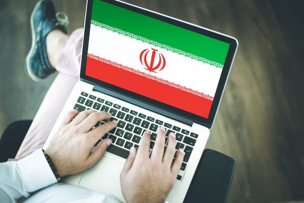 افرادی که از لپ تاپ استفاده می کنند و پرچم ایران را روی صفحه نمایش می دهند