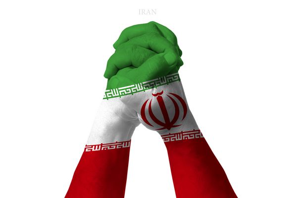مردی با دست های در هم گره شده منقش به پرچم ایران