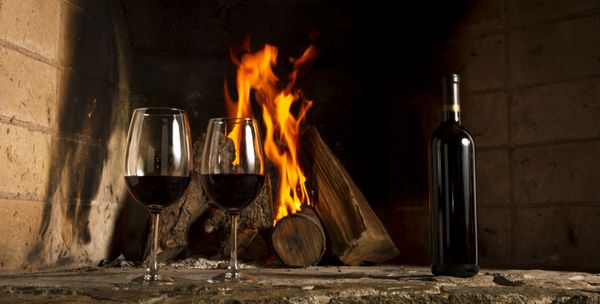 Copa de vino tino con fuego de chimenea de fondo