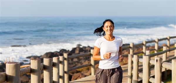 زن میانسال مناسب در حال دویدن در ساحل
