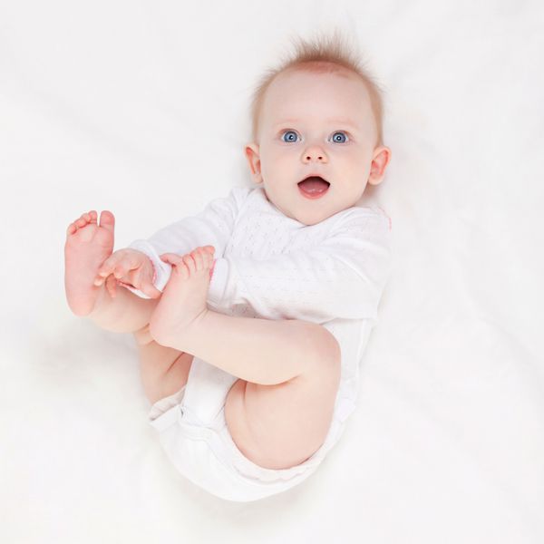 نوزاد ناز با چشمان آبی زیبا که در تخت سفید دراز کشیده است