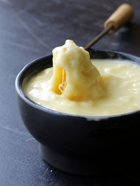 فوندو پنیر - تکه نان کروتون در یک پنیر مایع