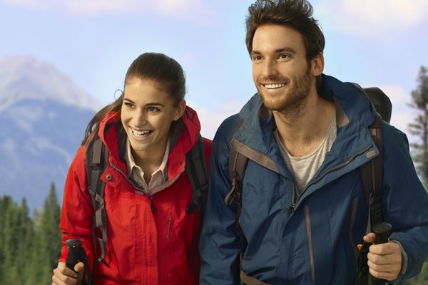 زوج کوهنوردی در حال بالا رفتن از سربالایی با لبخند