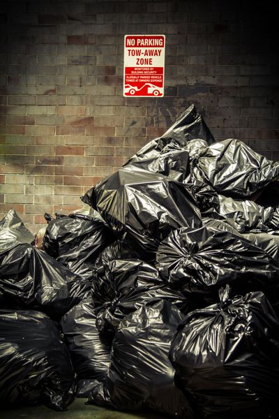 کیسه های زباله سیاه روی دیوار شهری انباشته شده است