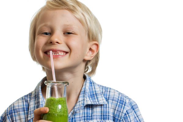 پسر ناز در حال نوشیدن اسموتی سبز در حال لبخند زدن