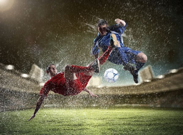 دو بازیکن فوتبال در حال ضربه زدن به توپ